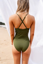 Model wearing a green swimsuit on the beach