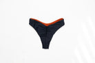 Flat lay of the Duo reversible bikini bottom in Midnight with the Sand side showing at the edge