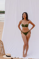 Full-length view of the Mila bandeau bikini set in forest green at the beach